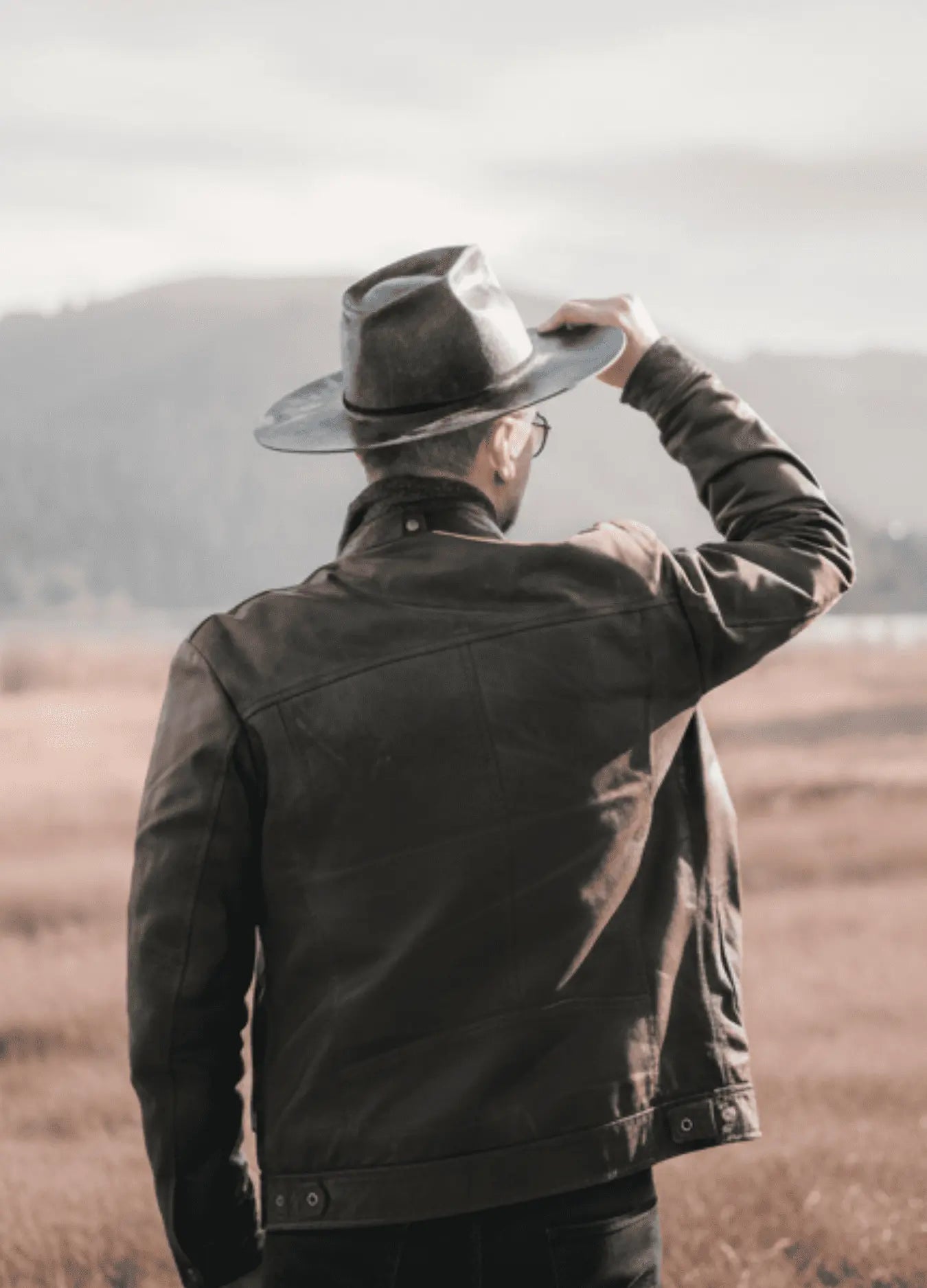 Person wearing a black jacket and hat in a desert landscape