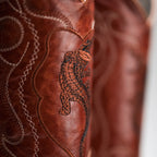 Close-up of a brown leather product with intricate stitching and a tiger design.