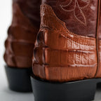 Close-up of brown leather boots with detailed texture on a light background