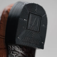 Close-up of a boot sole with a brand logo on a gray background