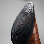 Close-up of a brown leather boot with embossed design and 'JOE' branding on a gray background