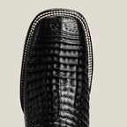 Close-up of a black crocodile-patterned boot sole on a beige background