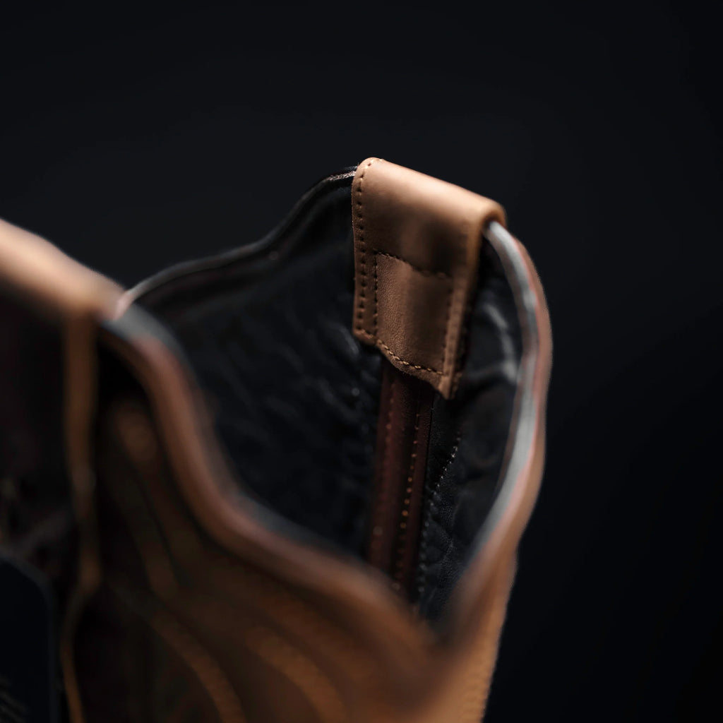 Close-up of a brown leather boot with a dark background