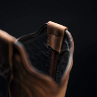 Close-up of a brown leather boot with a dark background