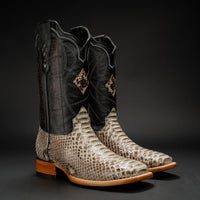 Pair of cowboy boots with black leather top and snake skin pattern on the sides against a dark background