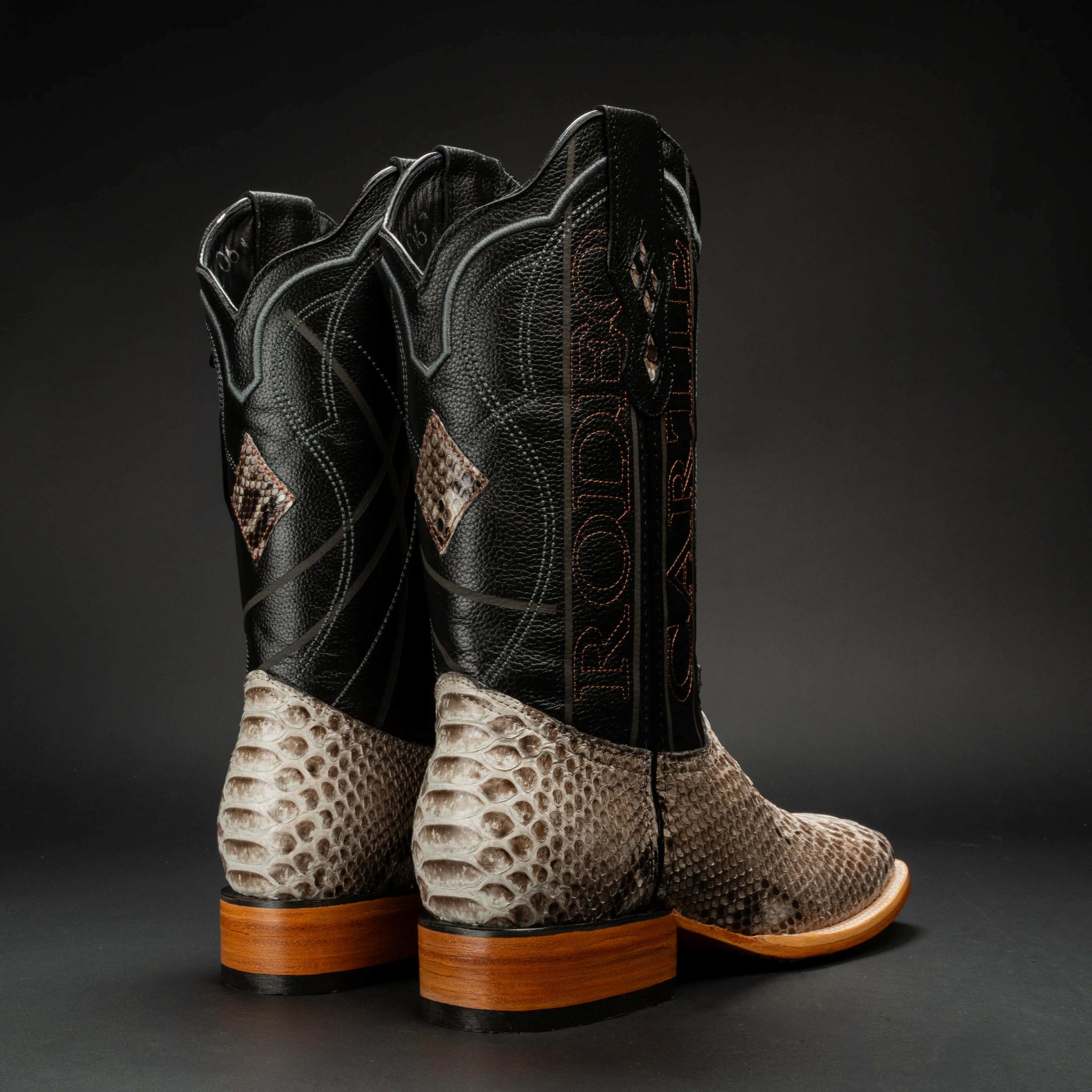 Pair of cowboy boots with snake skin pattern on a dark background