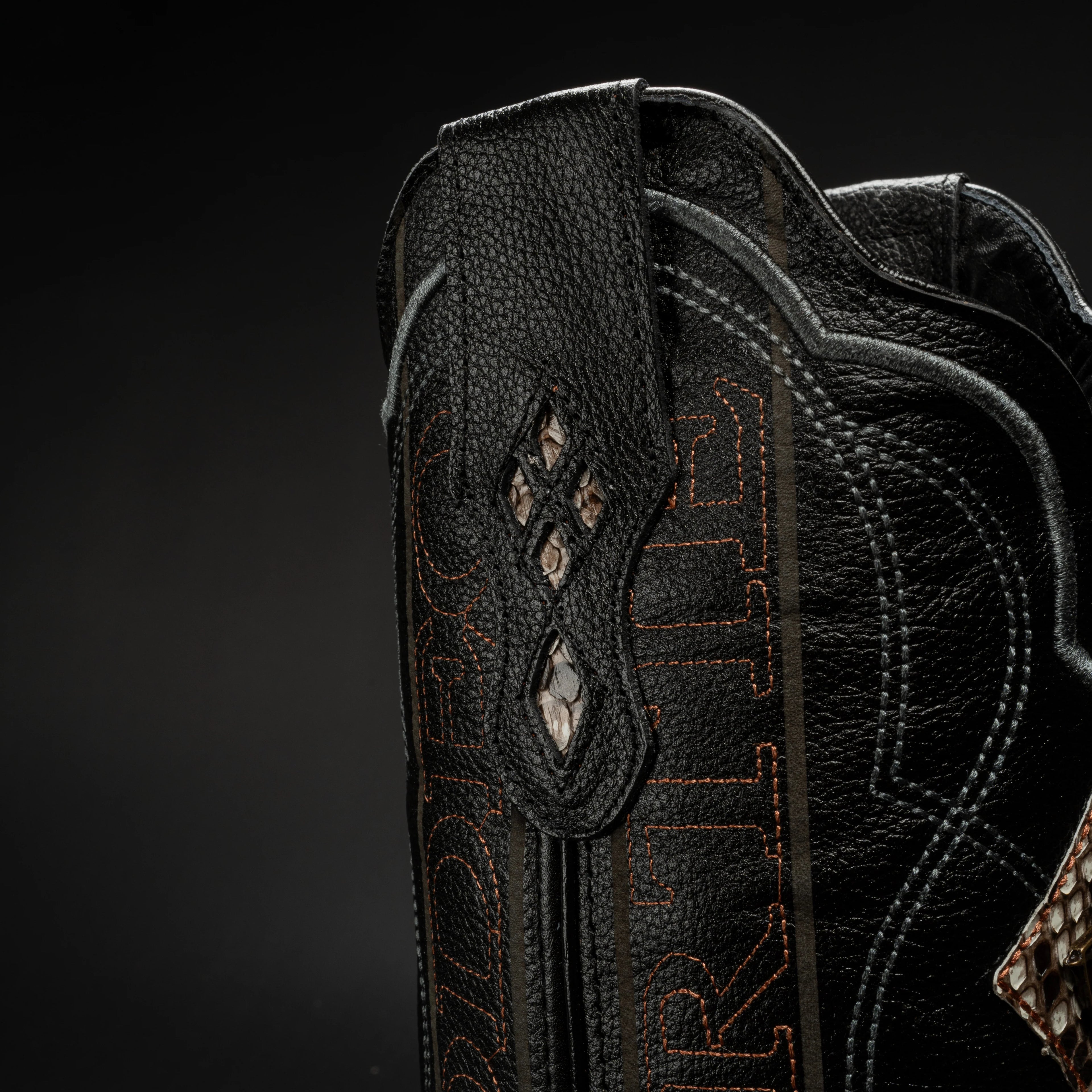 Close-up of a black leather boot with intricate stitching and patterns on a dark background