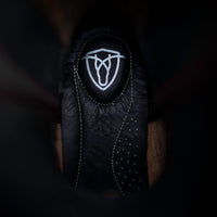 Black leather boot with a white emblem on a dark background