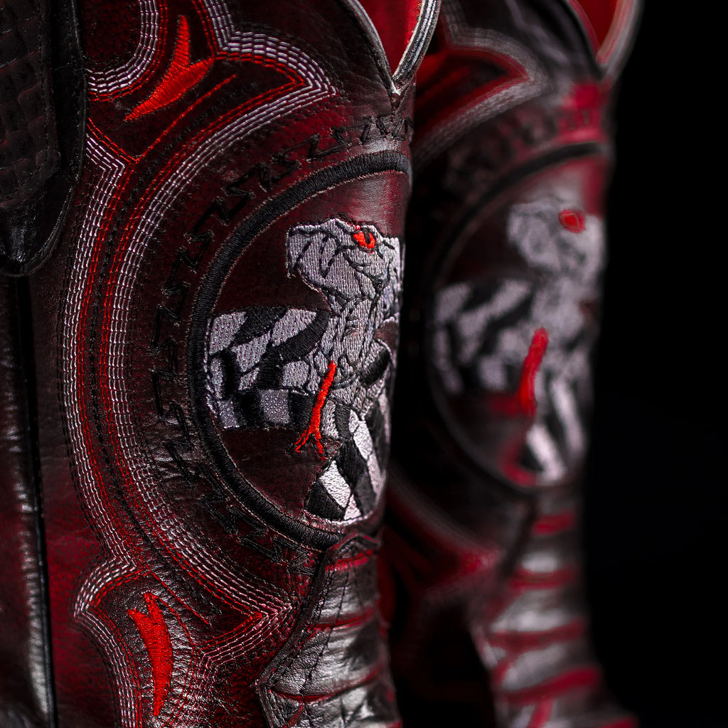 Close-up of a boot with intricate red and black designs and a wolf emblem.