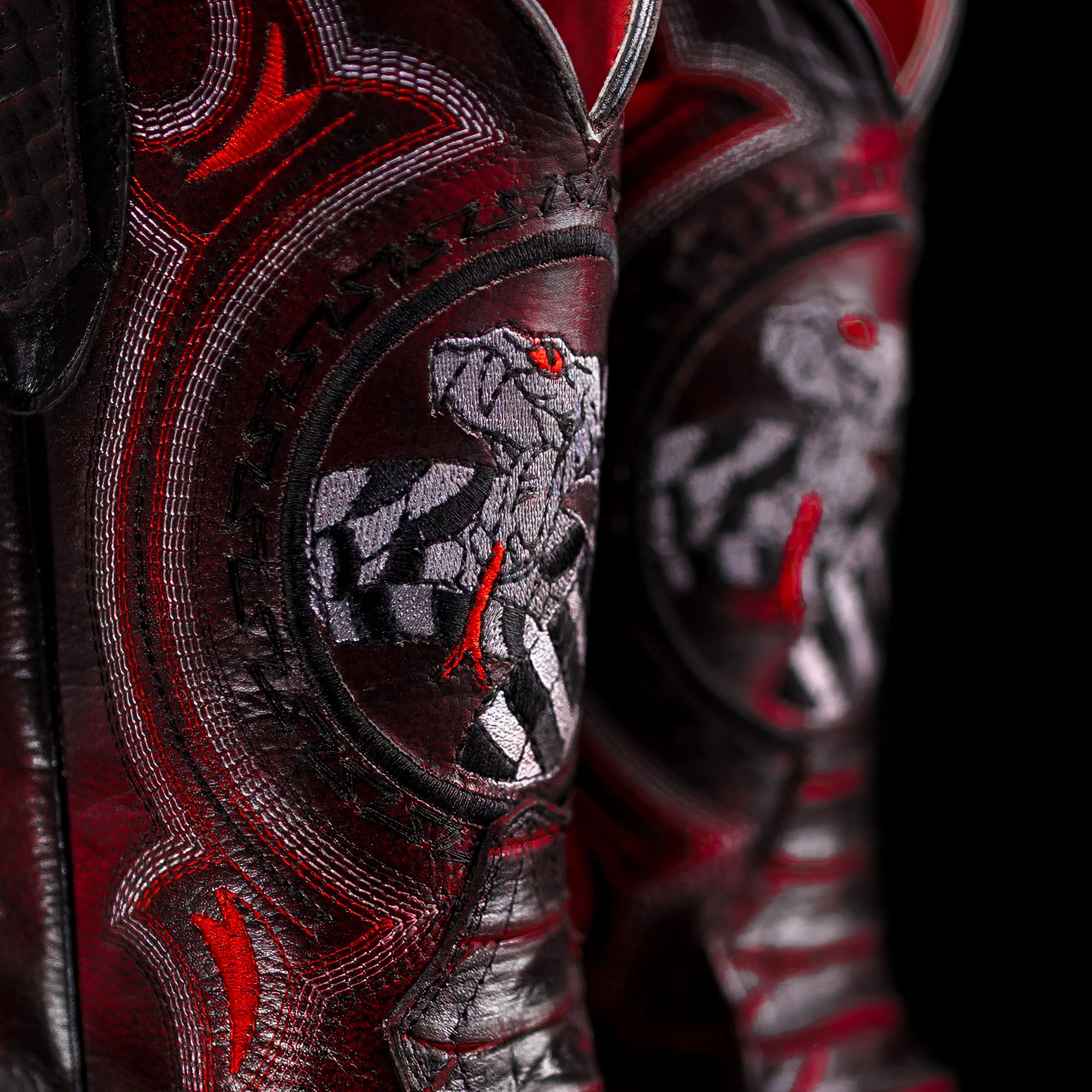 Close-up of a boot with intricate red and black designs and a wolf emblem.