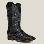 Black cowboy boot with intricate design on a beige background