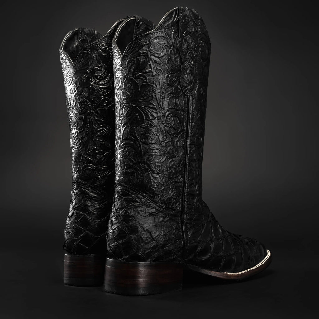 Pair of black cowboy boots with intricate designs on a dark background