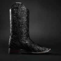 Black leather cowboy boot with intricate embossing on a dark background