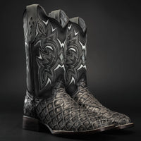 Black cowboy boot with intricate white embroidery on a dark background