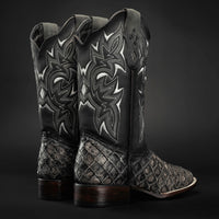Pair of black and silver cowboy boots with intricate designs on a dark background