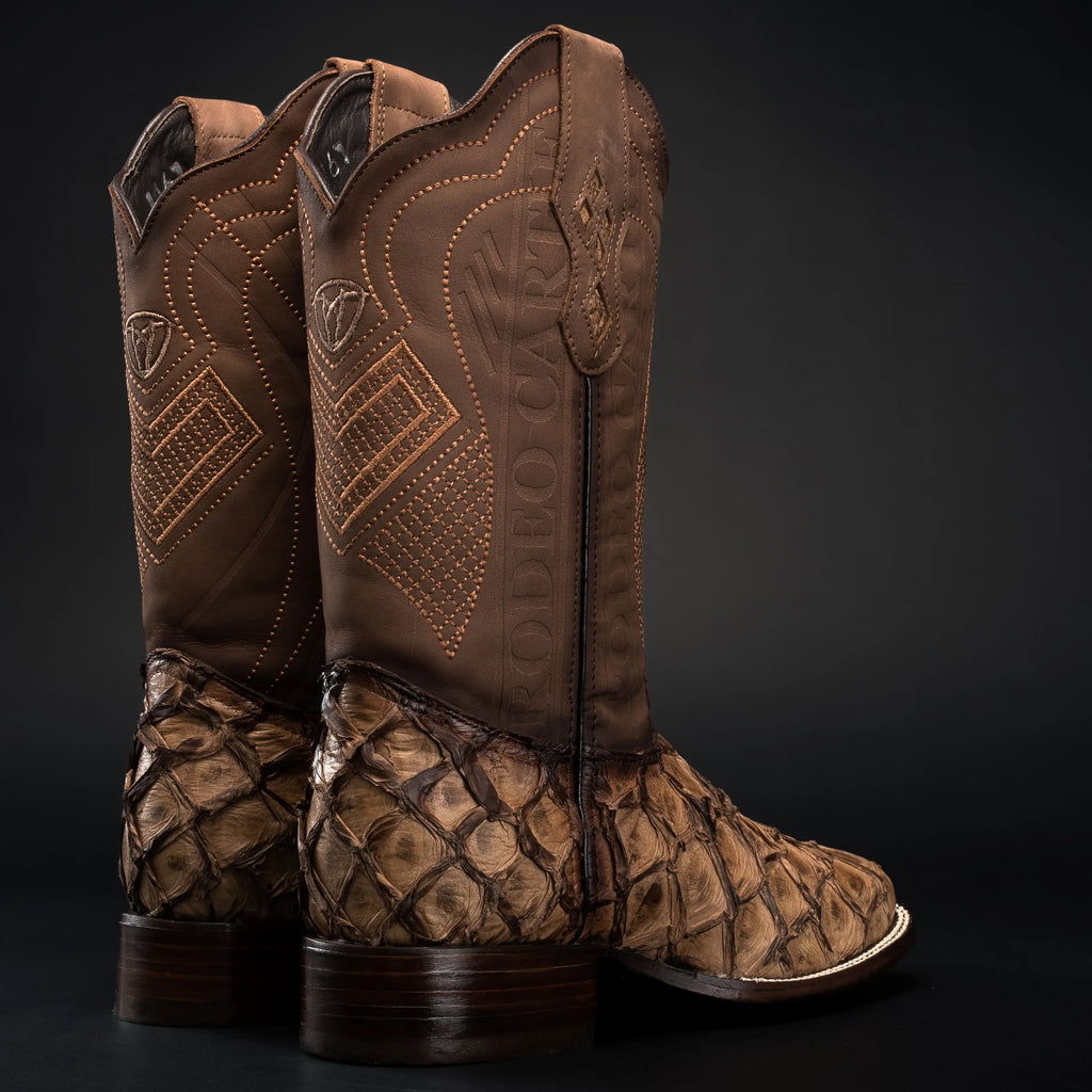 Pair of brown cowboy boots with patterned soles on a black background