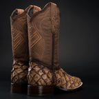 Pair of brown cowboy boots with patterned soles on a black background