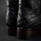 Close-up of dark brown leather boots with a textured finish on a dark background