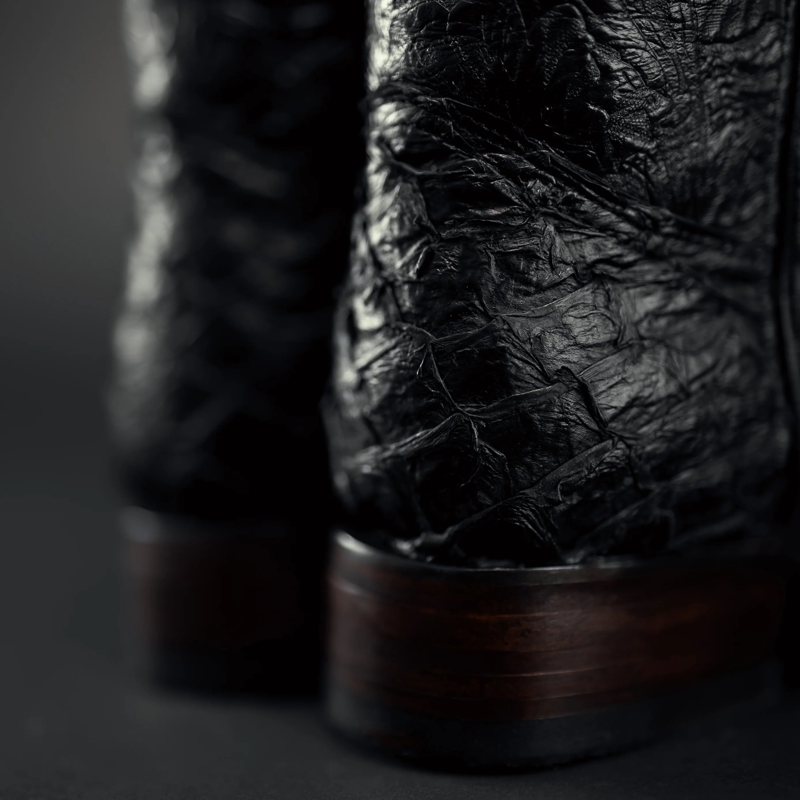 Close-up of dark brown leather boots with a textured finish on a dark background