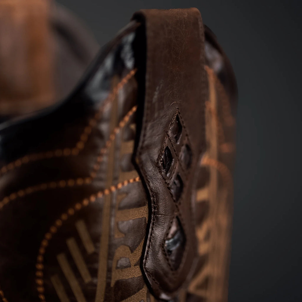 Close-up of a brown leather boot with intricate stitching on a dark background