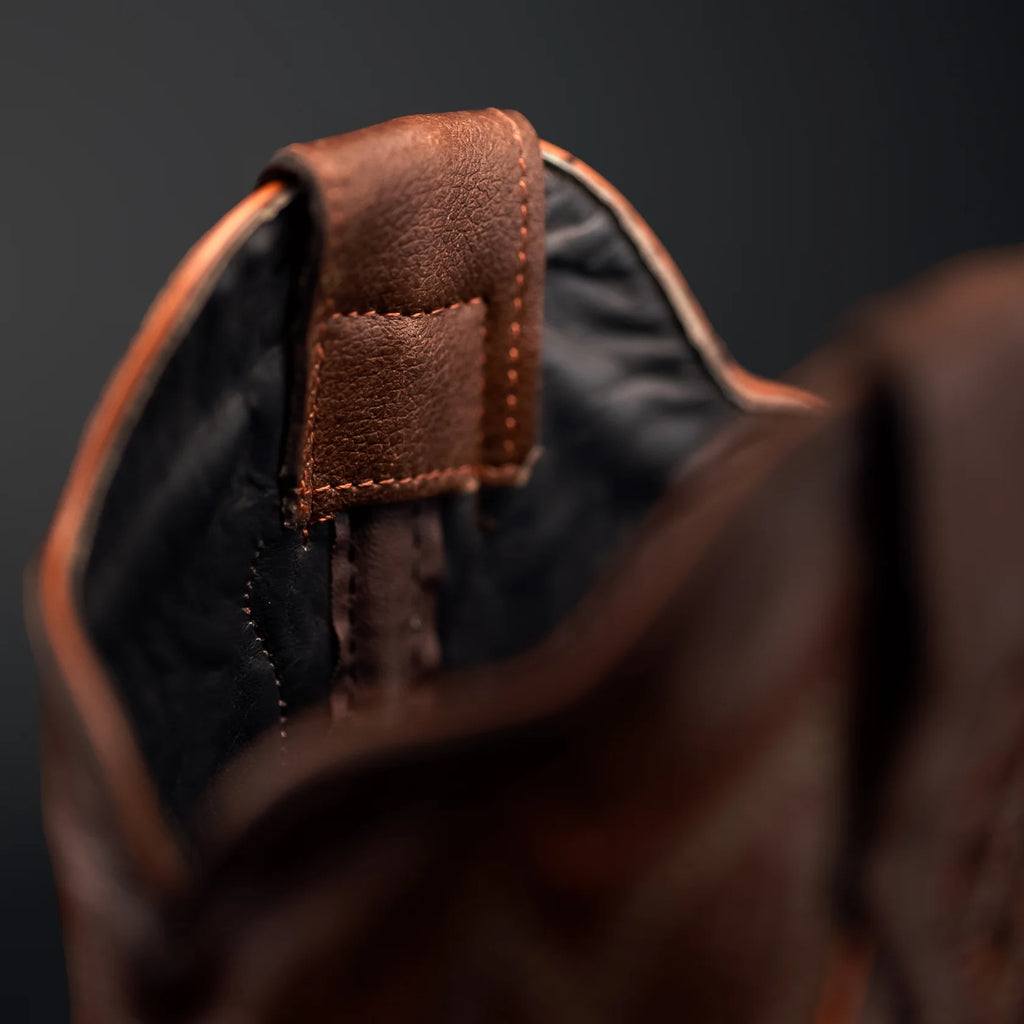 Close-up of a brown leather bag with a dark background