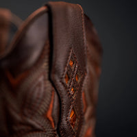 Close-up of a brown leather product with intricate stitching on a dark background