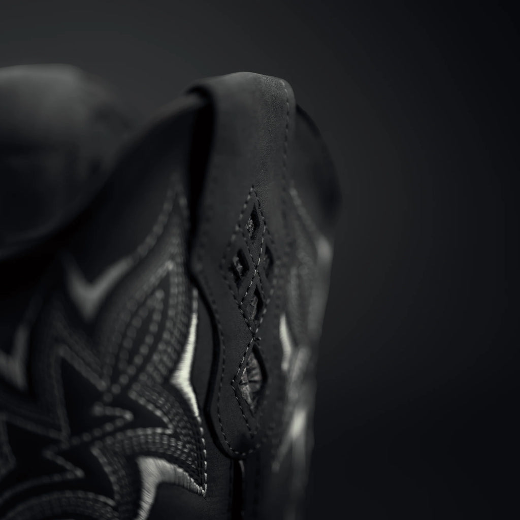 Close-up of a black leather shoe with intricate patterns on a dark background