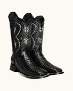Black cowboy boots with intricate designs on a white background